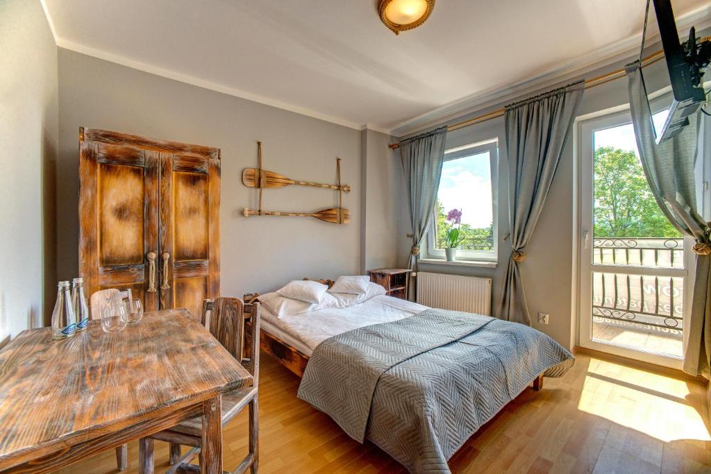 1 dormitorio con cama, mesa y ventanas en Noclegi Reda en Polańczyk