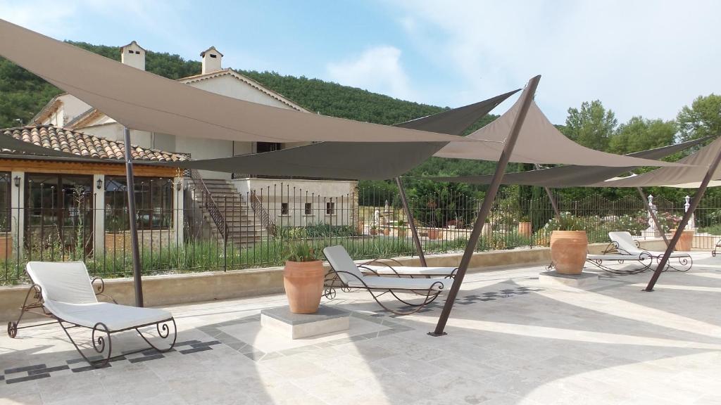 a group of chairs and umbrellas on a patio at Bastide De Mazan in Riez