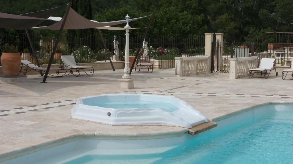 a swimming pool with a bathtub in the middle of it at Bastide De Mazan in Riez