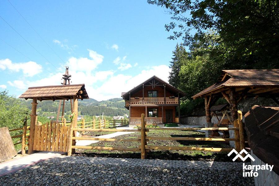 une maison avec une clôture et un portail en bois dans l'établissement Karpatska Oselia, à Verkhovyna