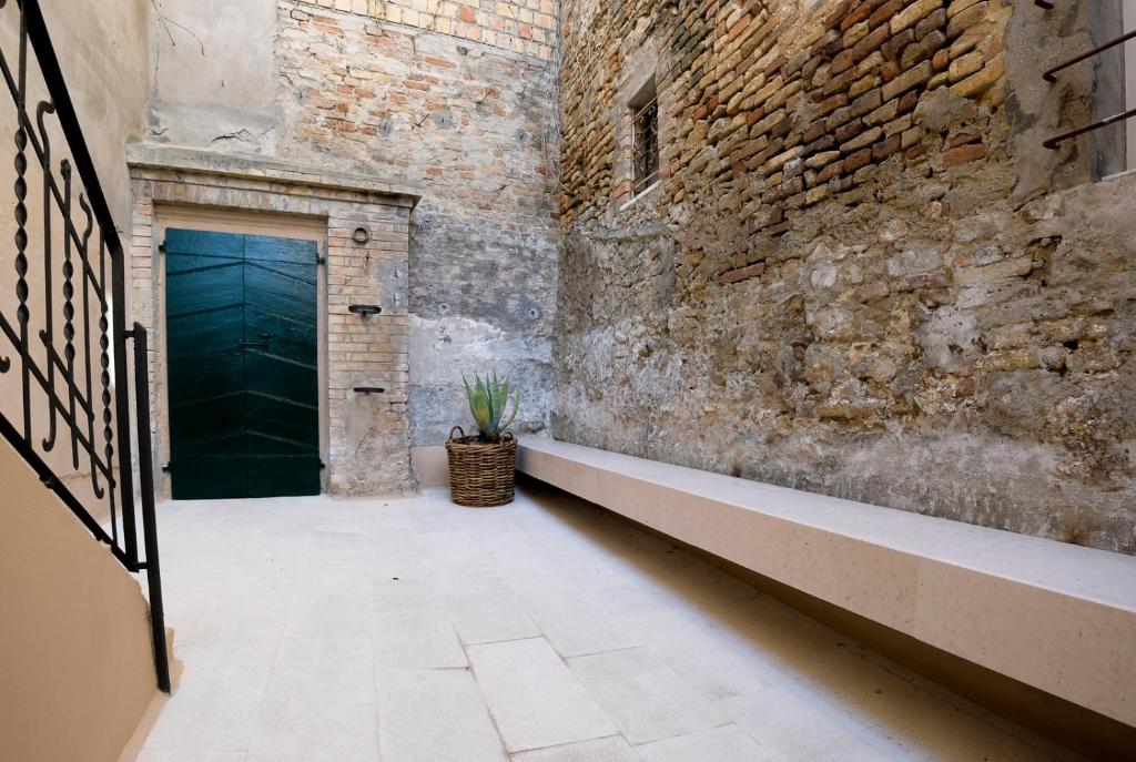 a hallway with a green door and a brick wall at Cortile nel borgo in Marina Palmense