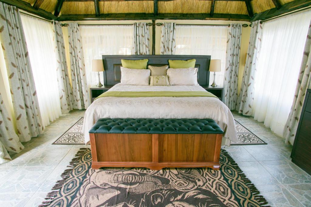 a bedroom with a large bed with a green bench at Art Lodges in Harare