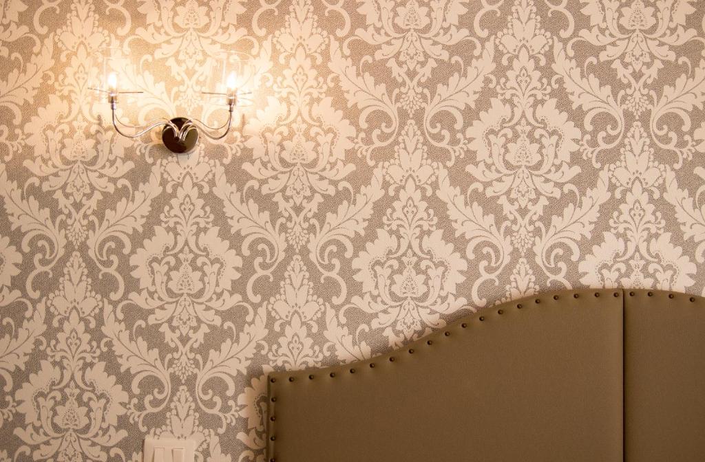 Habitación con pared cubierta de papel pintado y espejo. en Hotel Lo Scudiero en Turín