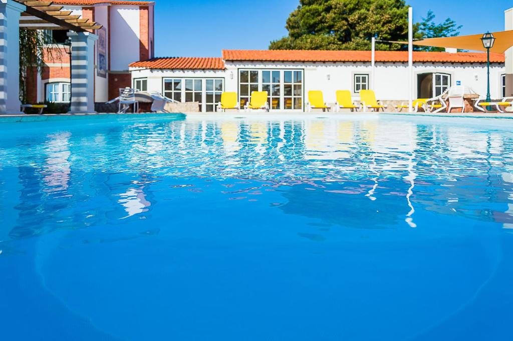 uma piscina com água azul e cadeiras amarelas em Casa Da Padeira - Turismo Rural em Alcobaça