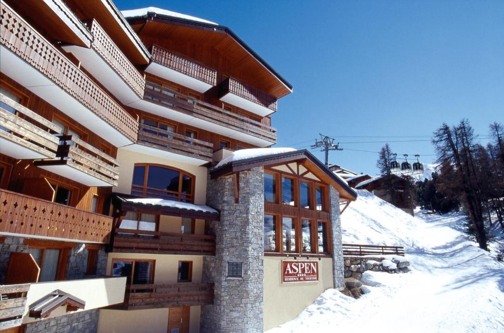 Un edificio nella neve con un cartello sopra di travelski home select - Résidence Aspen 4 étoiles a Mâcot La Plagne