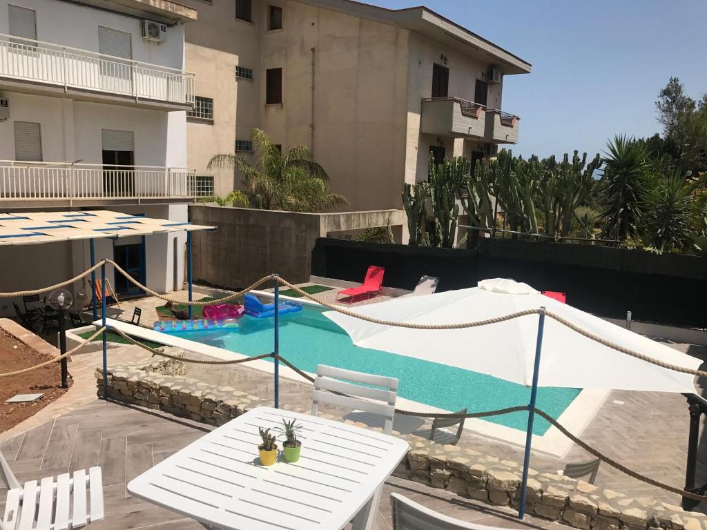 a pool with a table and a hammock next to a building at Residence del Golfo in Castellammare del Golfo