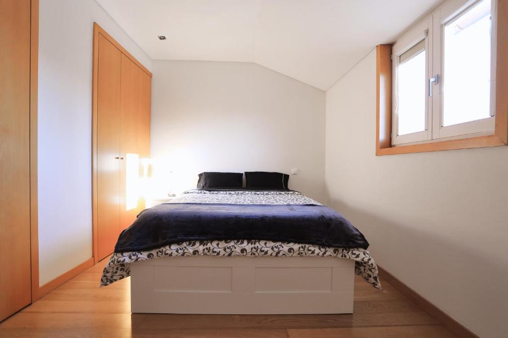 a bedroom with a bed with a black and white bedspread at Bright Luxury Apartment in Viana do Castelo