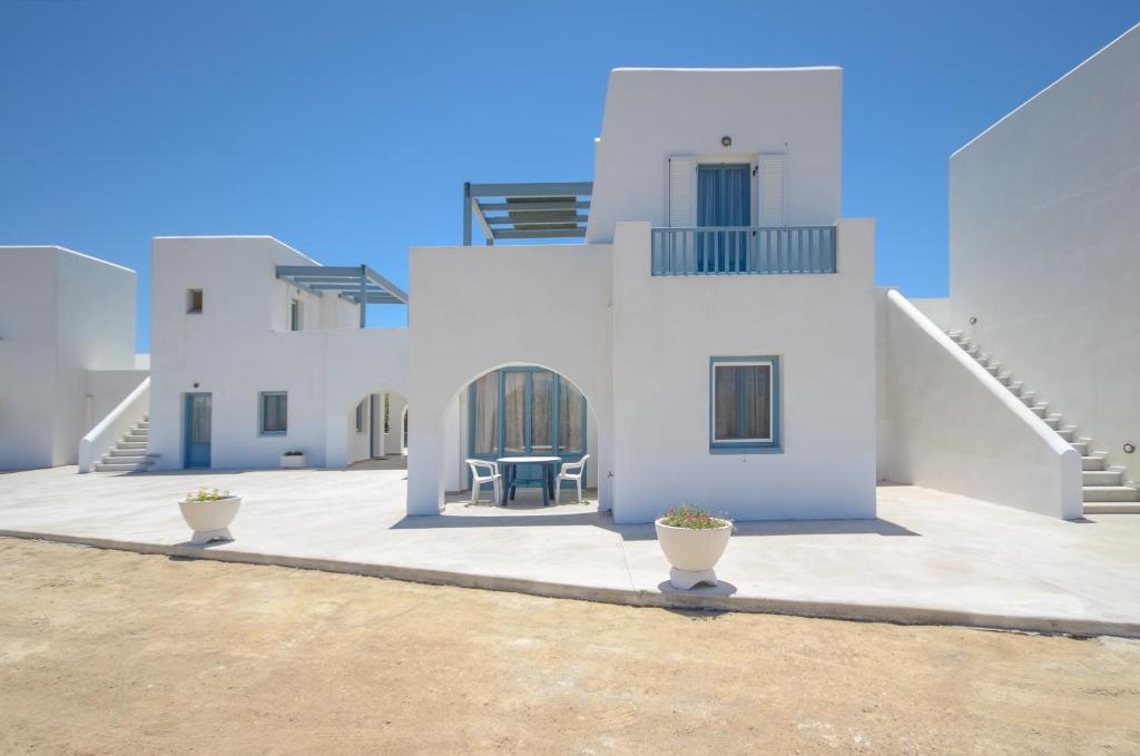 a white house with two chairs in the courtyard at Apartments Naxos Camping in Naxos Chora