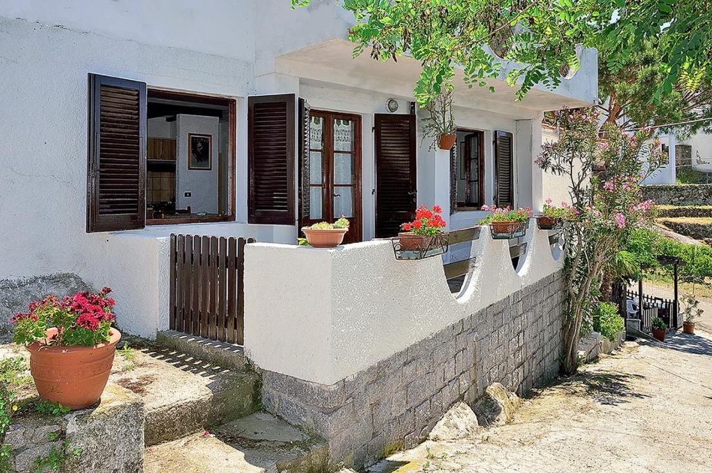 una casa bianca con piante in vaso su un muro di Appartamento vista mare a La Guardia