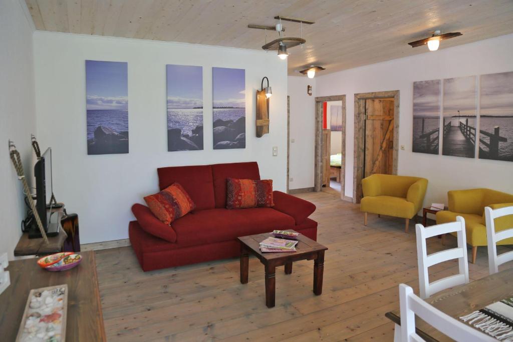 salon z czerwoną kanapą i stołem w obiekcie Ferienhaus-Rotdorn-Haus-Nord w mieście Strukkamp auf Fehmarn
