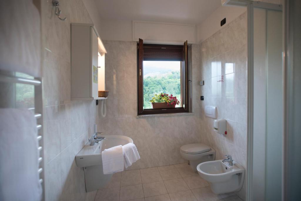 uma casa de banho com um lavatório, um WC e uma janela. em Hotel la Colletta em Paesana