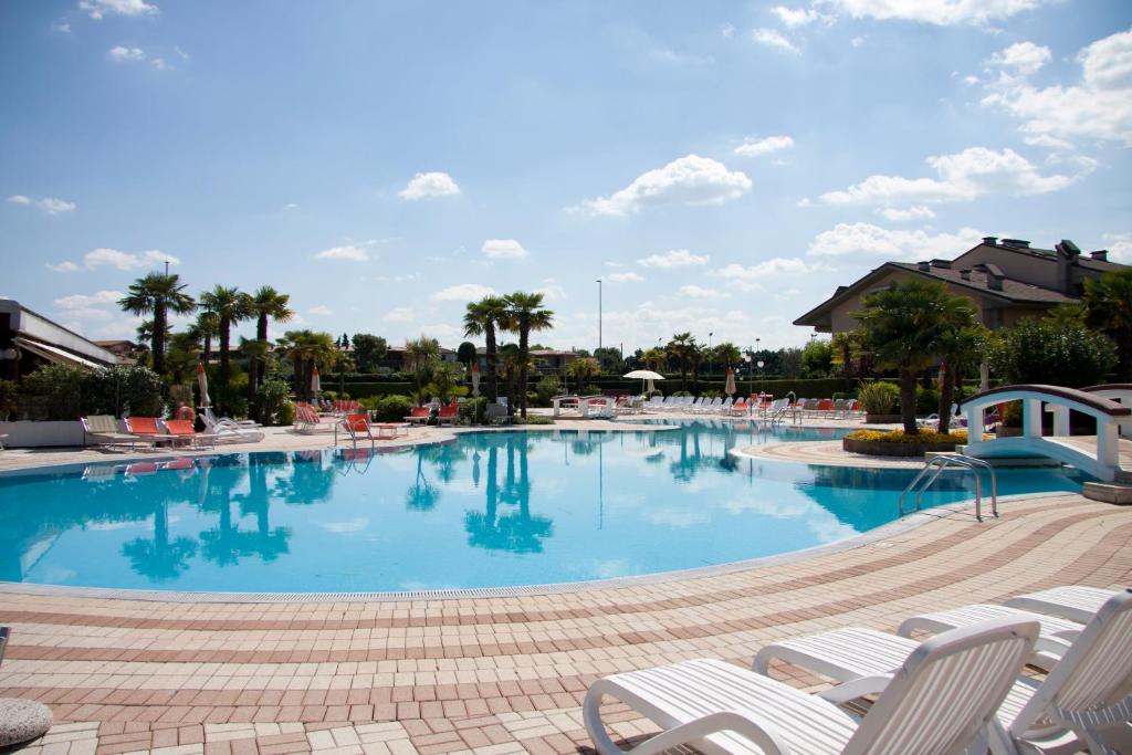 una grande piscina con sedie e palme di Lauri & Faggi a Desenzano del Garda