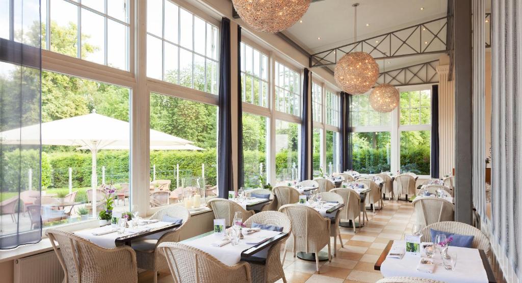 ein Restaurant mit Tischen, Stühlen und Fenstern in der Unterkunft A-ROSA Travemünde in Travemünde