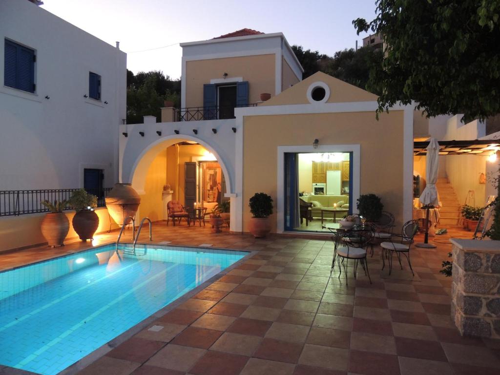 a villa with a swimming pool in front of a house at Marouso Villa in Panormos Kalymnos