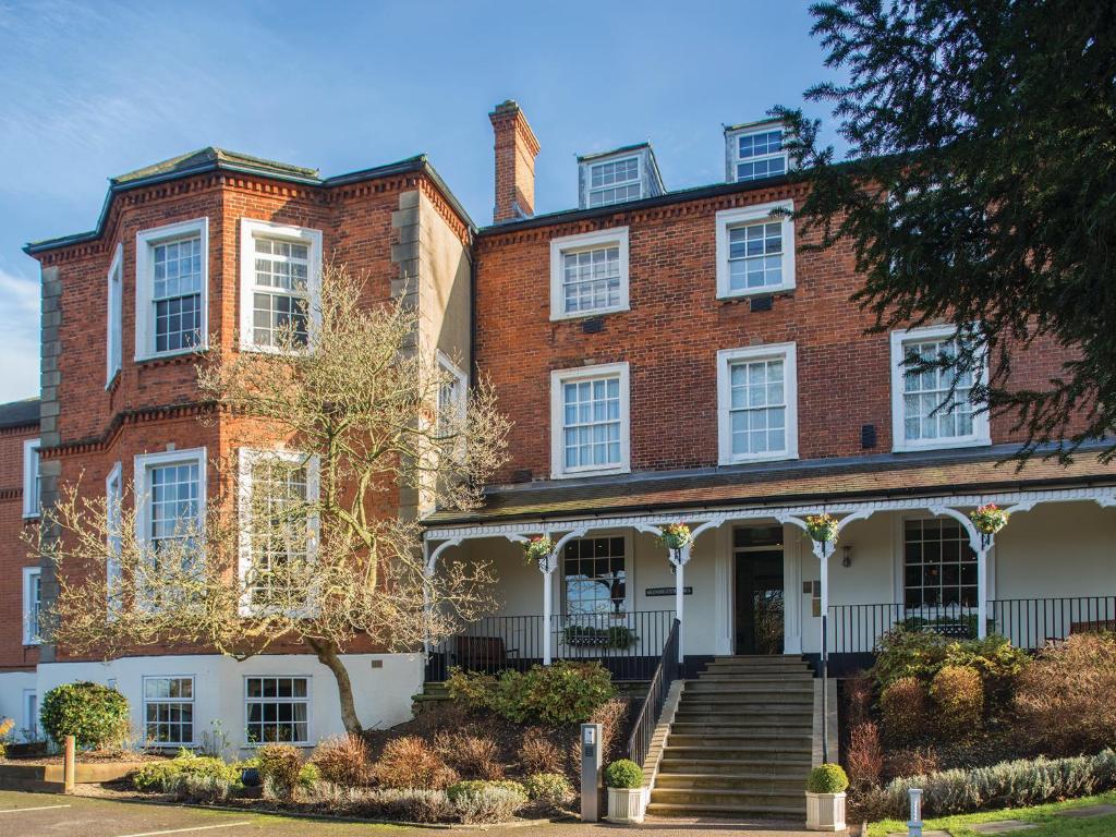 a large brick building with stairs in front of it at Brandshatch Place & Spa in Ash