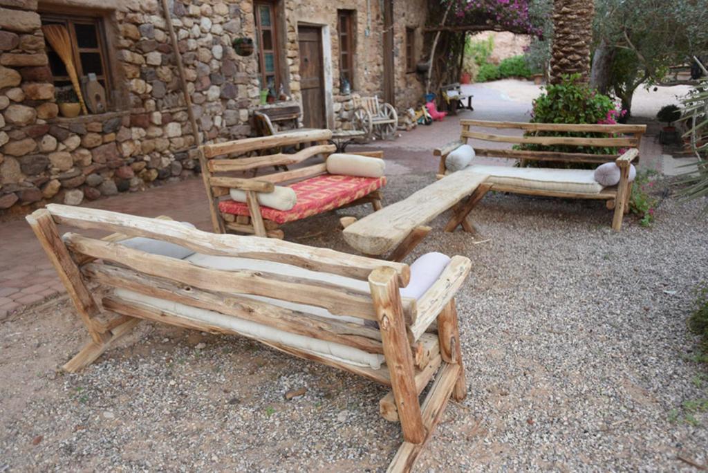 drei Holzbänke vor einem Gebäude in der Unterkunft Williams House in Eilat