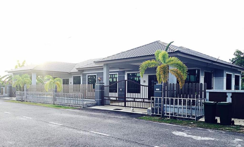 a house with a fence and a palm tree in it at Homestay Melaka Urich in Malacca