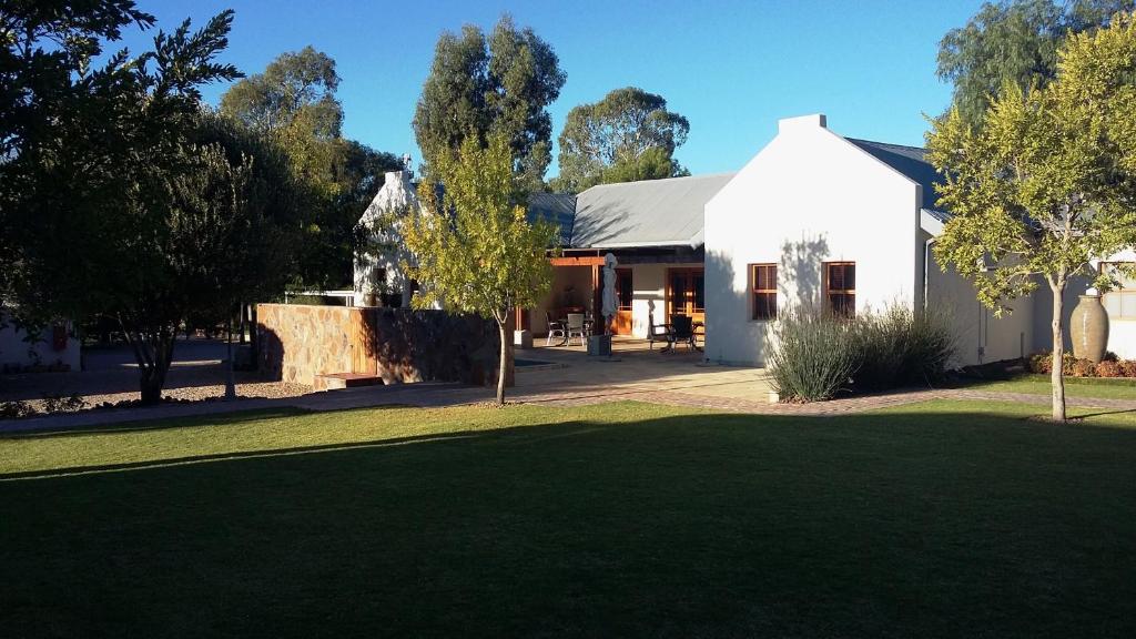 a white house with a lawn in front of it at Honeylocust Guesthouse in Colesberg