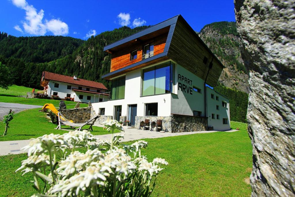 ein Haus auf einem grünen Feld mit Blumen in der Unterkunft Apart Arve in Sankt Leonhard im Pitztal