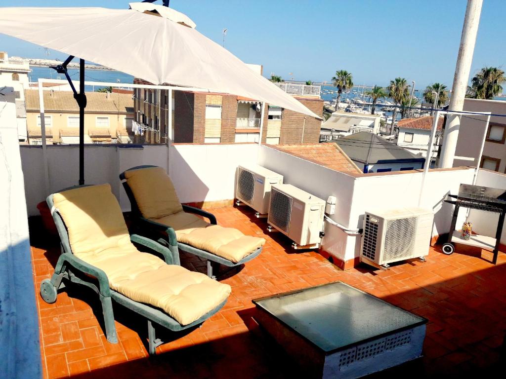 un patio avec deux chaises et un parasol sur le toit dans l'établissement Apartamento Villananitos, à San Pedro del Pinatar