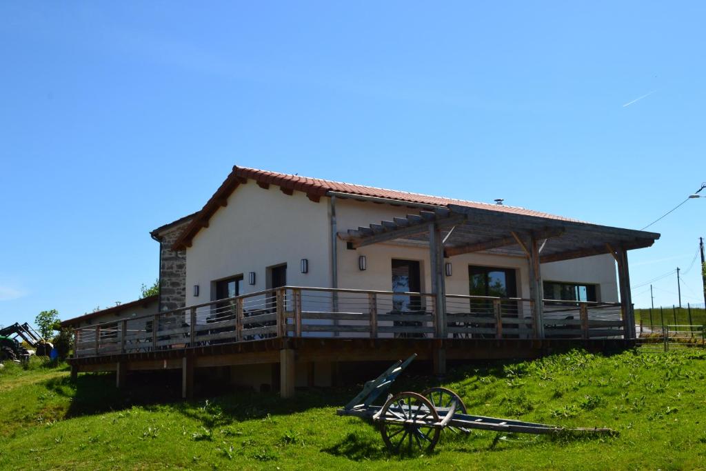 ein Haus auf einem Hügel mit einer Holzterrasse in der Unterkunft Auberge BRIASSOU in Grazac