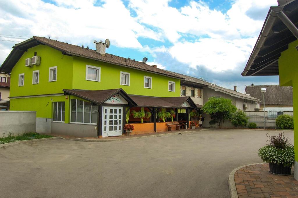 a yellow house with a parking lot in front of it at Penzion Pri Slovenc in Dol pri Ljubljani