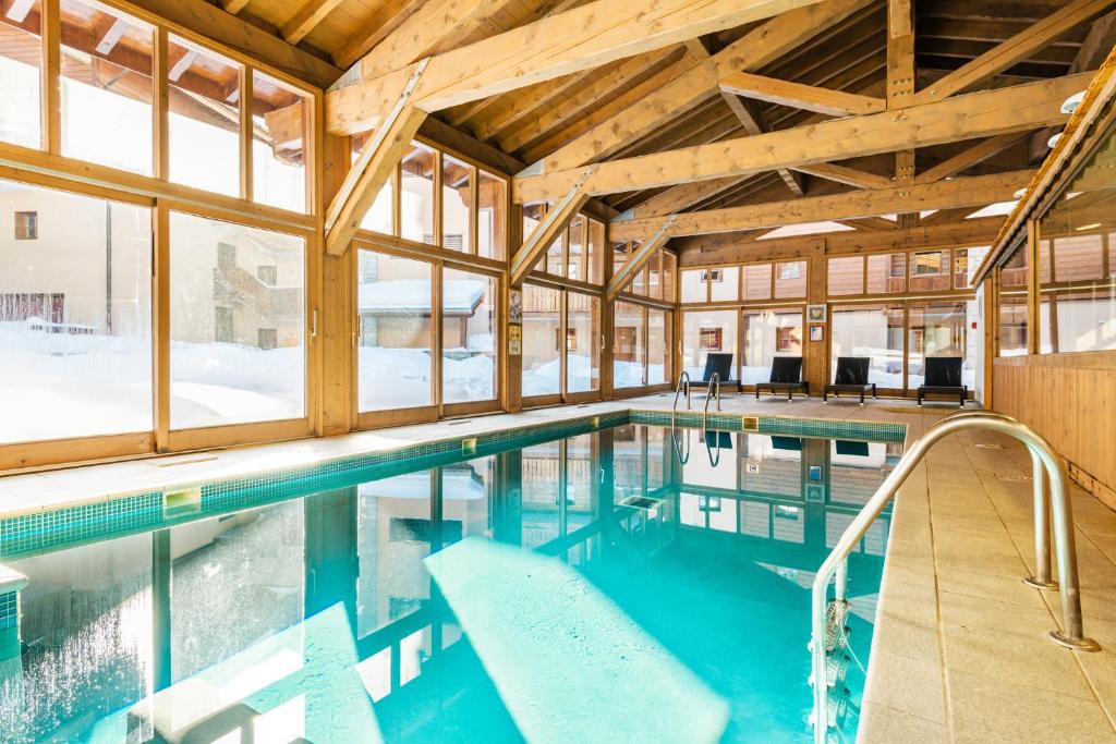 uma piscina num edifício com janelas em travelski home premium - Résidence Les Chalets d'Edelweiss 4 étoiles em Plagne 1800