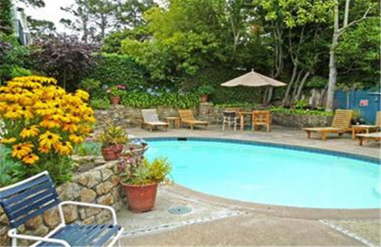 a garden area with a pool and a bench at Normandy Inn in Carmel