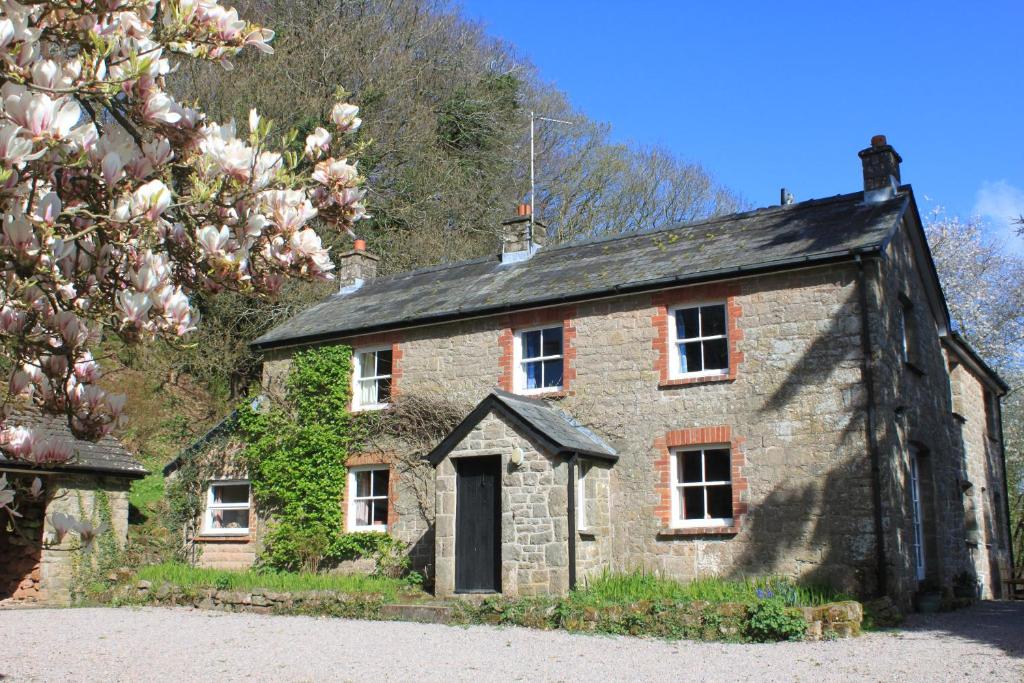 una vecchia casa in pietra con un albero fiorito di Church Hill Farm a Monmouth