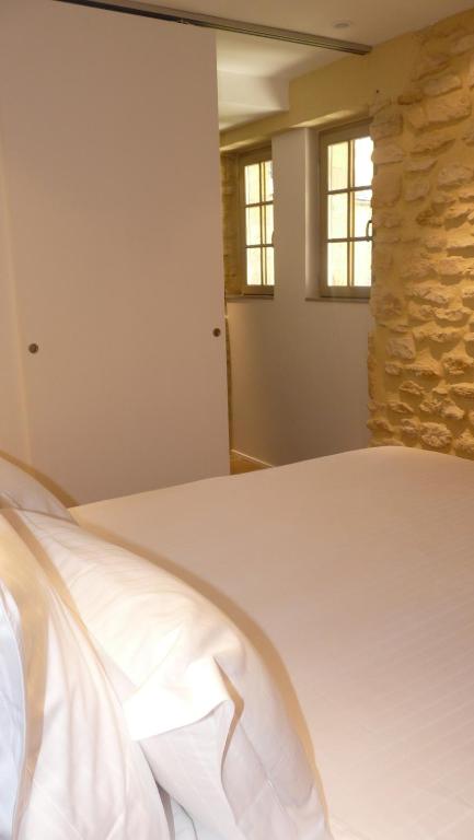 a bedroom with a white bed with two windows at Le Porche de Sarlat in Sarlat-la-Canéda