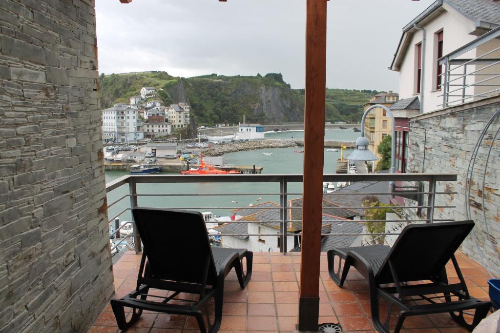 a balcony with two chairs and a view of a harbor at Apartamentos turísticos Vistademar in Luarca