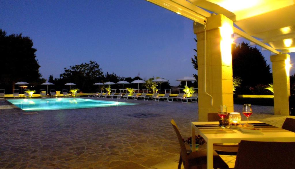 a pool with tables and umbrellas at night at La Casina Di Borgagne in Borgagne