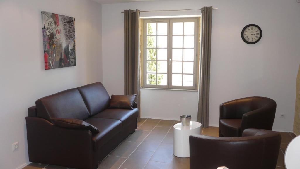 a living room with a leather couch and two chairs at Le Porche de Sarlat in Sarlat-la-Canéda