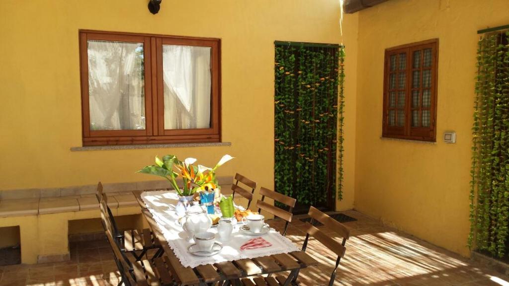 una mesa de comedor con sillas y flores. en B&B DOMU INCANTO Sa Domu sarrabesa, en Muravera