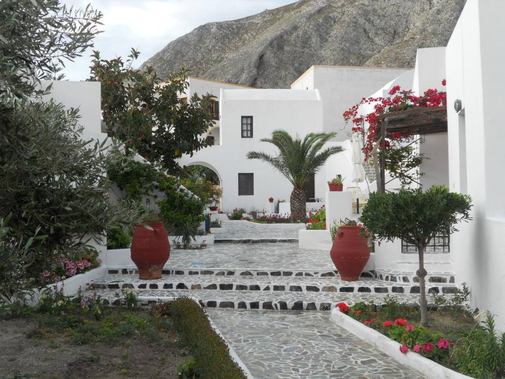 a courtyard of a white building with flowers and plants at Villa Ostria in Kamari