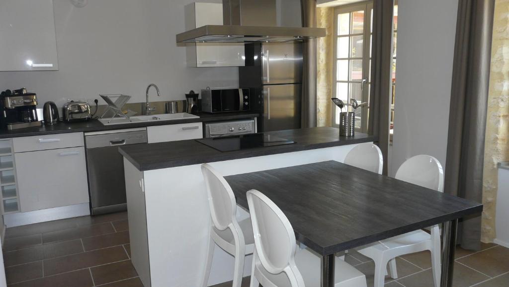 a kitchen with a wooden table and white chairs at Le Porche de Sarlat in Sarlat-la-Canéda