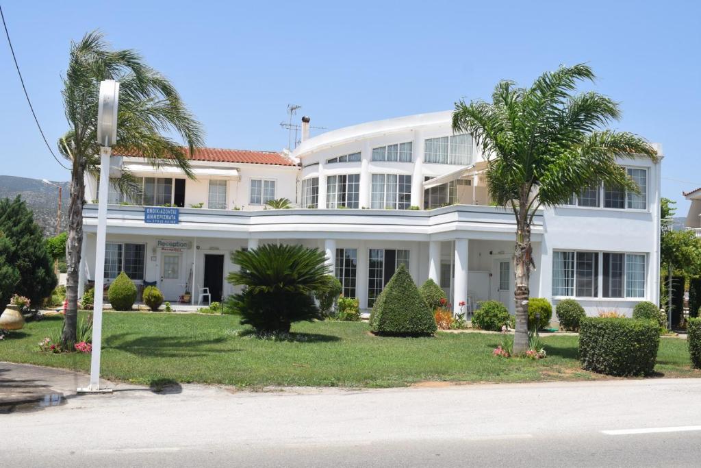 um edifício branco com palmeiras em frente em Miloi Rooms and Apartments em Míloi