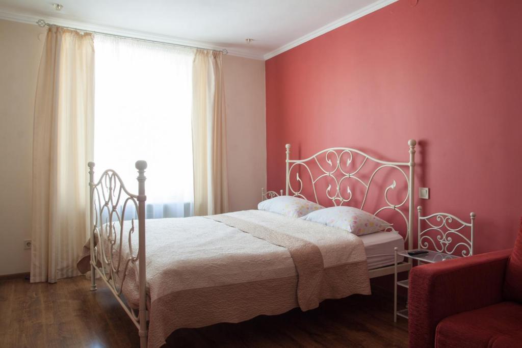 リヴィウにあるApartment Roksolana 2の白いベッドと赤い壁が備わるベッドルーム1室が備わります。