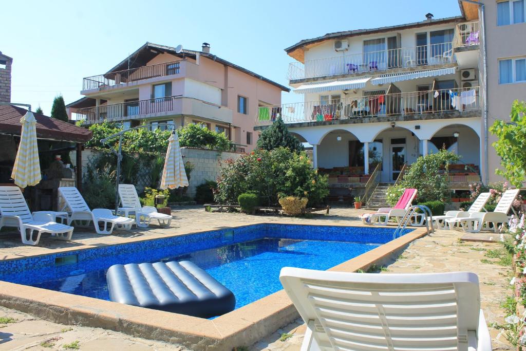 a swimming pool with lounge chairs and a hotel at The White House in Bliznatsi