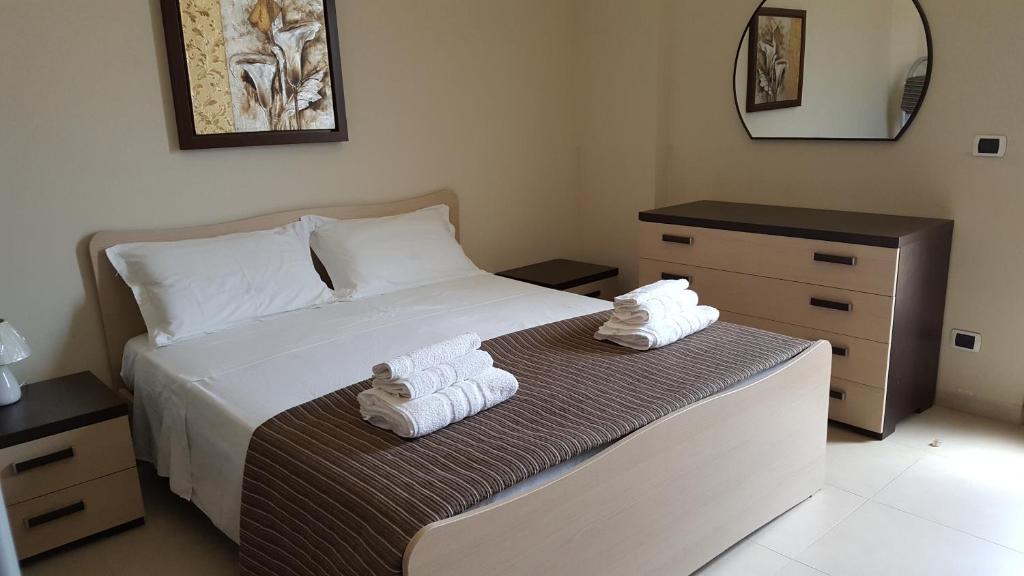 1 dormitorio con 1 cama con toallas en Appartamenti Emblema Mancaversa, en Marina di Mancaversa