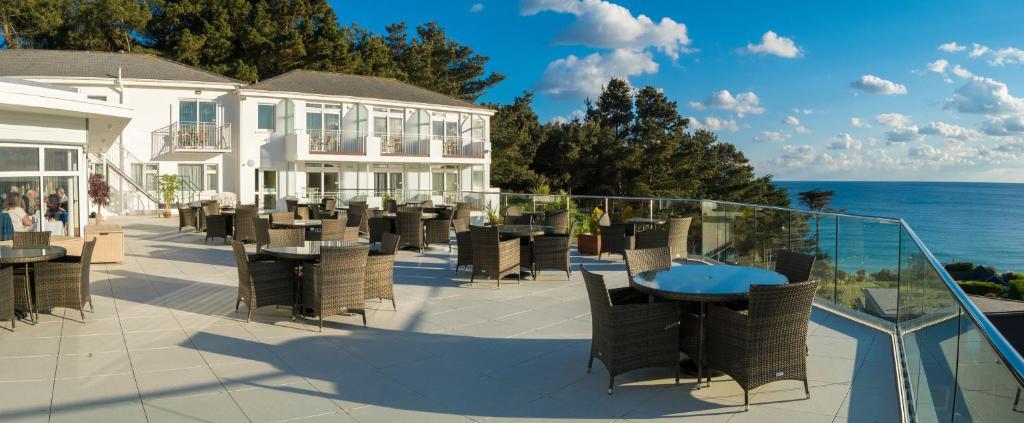 un patio con tavoli, sedie e vista sull'oceano di Biarritz Hotel a St Brelade