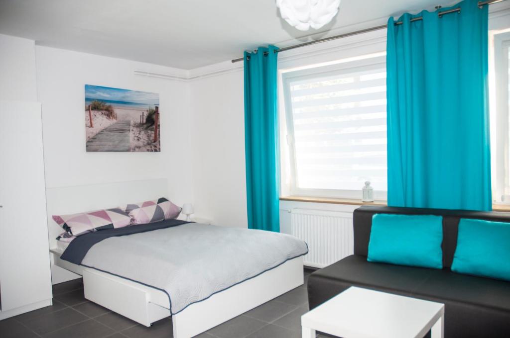 ブワディスワボボにあるPokoje gościnne Lisaのベッドルーム(青いカーテン、ベッド1台、ソファ付)
