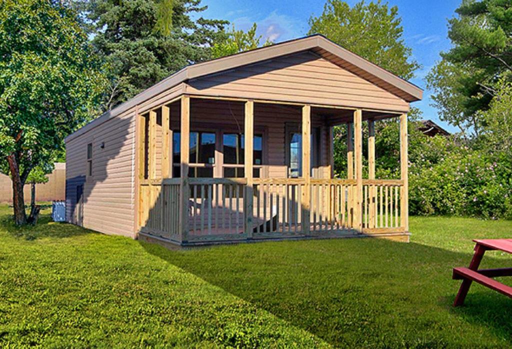 a small cabin with a porch in the grass at Green Mountain Park in Lenoir