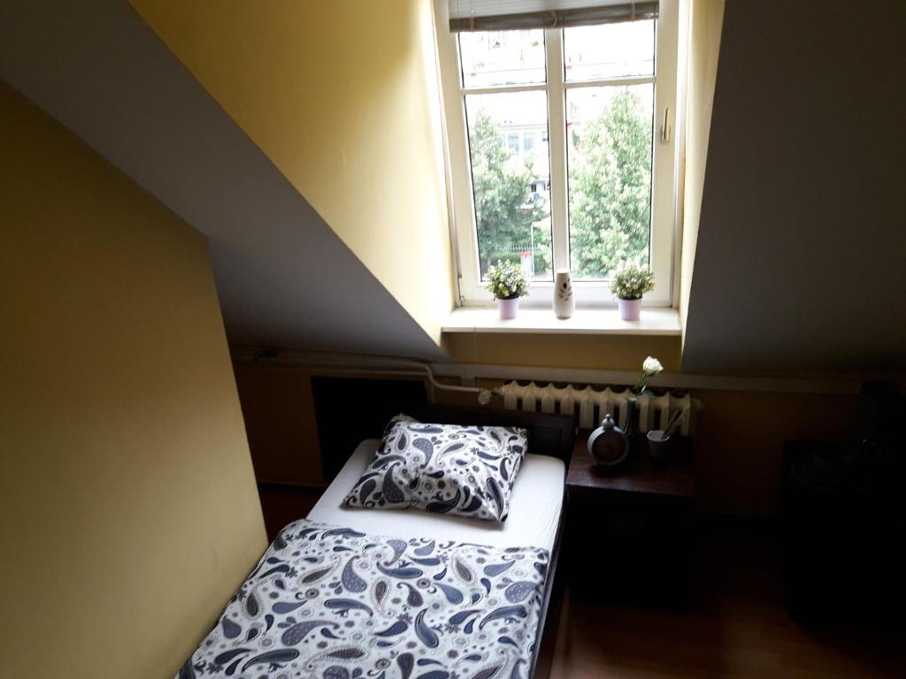 niewielka sypialnia z łóżkiem i oknem w obiekcie Hostel Pałacyk w Bydgoszczy