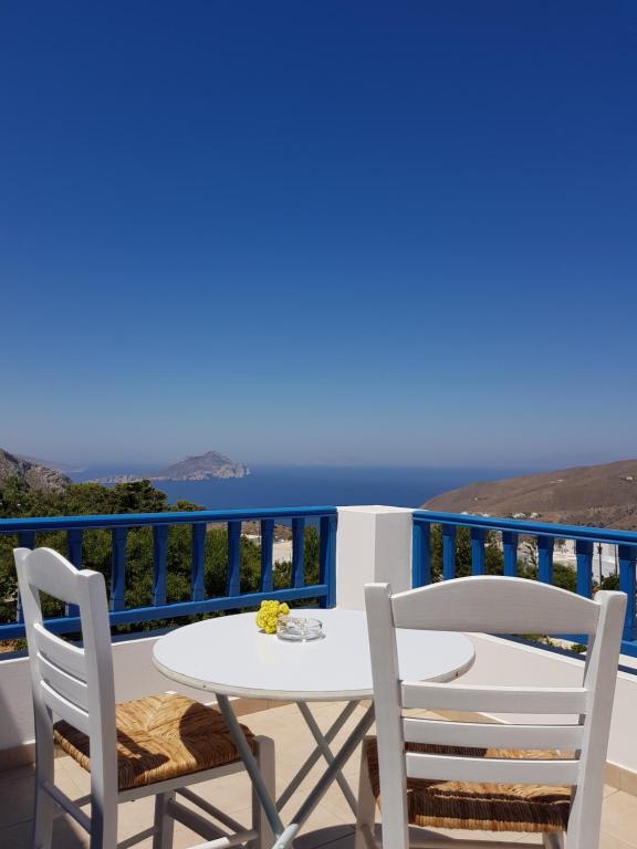 a table and chairs on a balcony with a view of the ocean at Amaranto Rooms in Aegiali