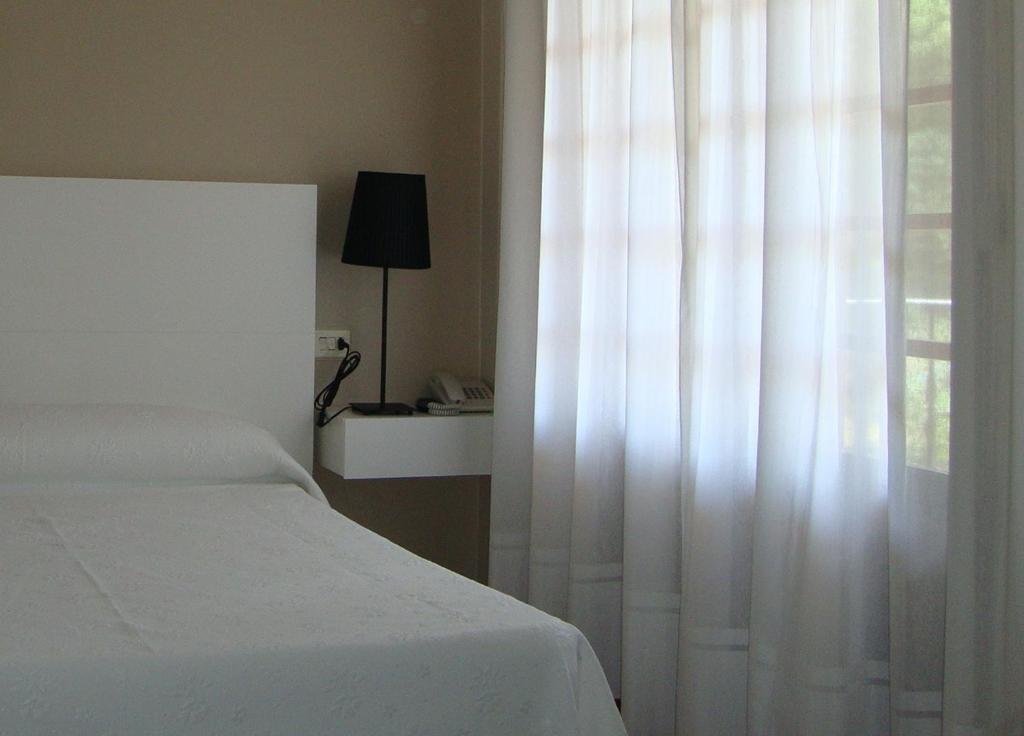 sypialnia z białym łóżkiem i oknem w obiekcie Hotel Chancelas w mieście Chancelas