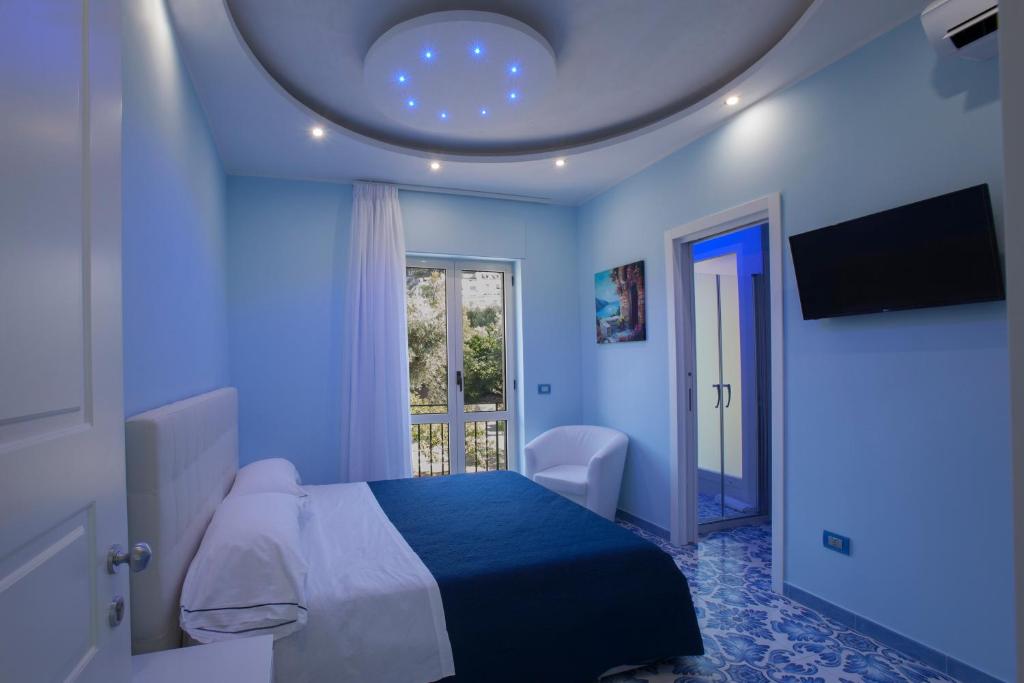 ein blaues Schlafzimmer mit einem Bett und einem Fenster in der Unterkunft Golfo Delle Sirene in Sorrent