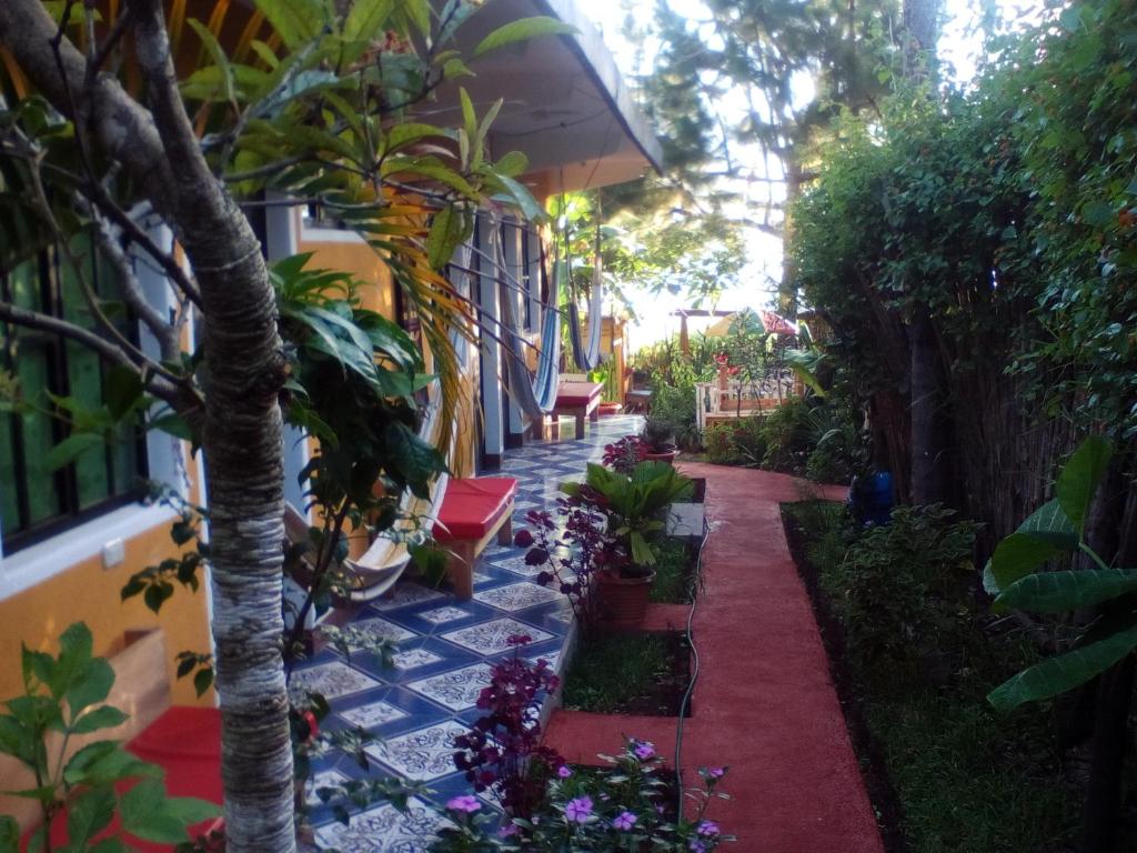 a garden with a pathway with flowers and a tree at Hotel y Restaurante Playa Linda in San Pedro La Laguna