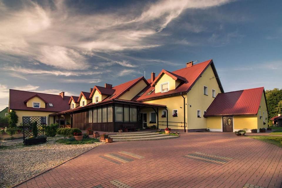 een groot huis met rode daken op een stenen oprit bij Zacisze Mazury in Kętrzyn