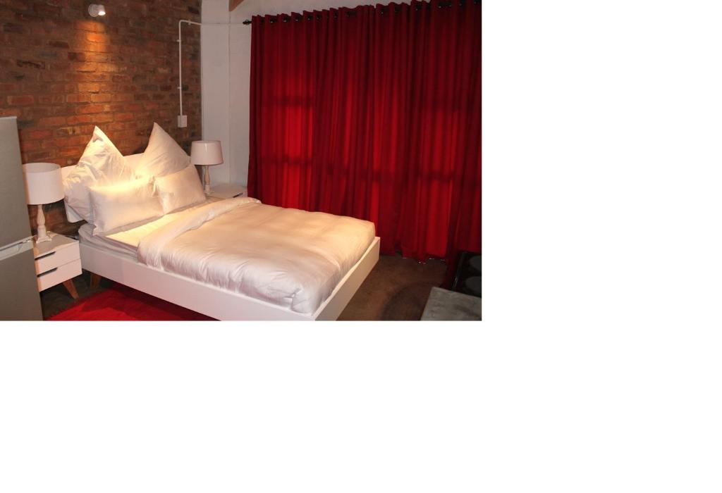 a bedroom with a bed with a red curtain at Forty Towers Apartments in Johannesburg